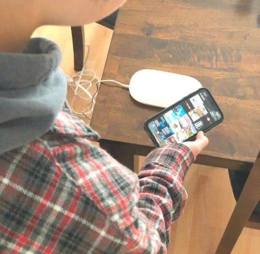 boy holding iphone over ixpand charger