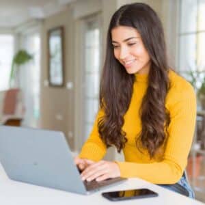 Smiling woman typing on laptop in a home