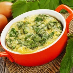 Casserole with nettle, eggs and cheese in a ceramic pots