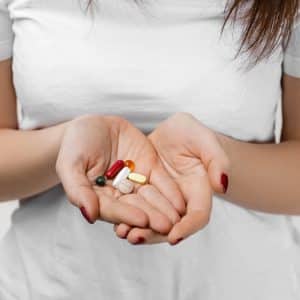 Young woman taking D3 and K2 tablets in her hand