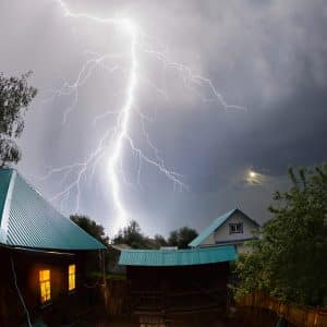 Lightening bolt over a house in a village at night
