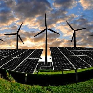 solar panels and wind turbines against a sunset