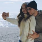 Very Happy Couple In Love Taking Selfie On The Beach in autmun day