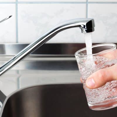 pouring tap water from faucet into glass