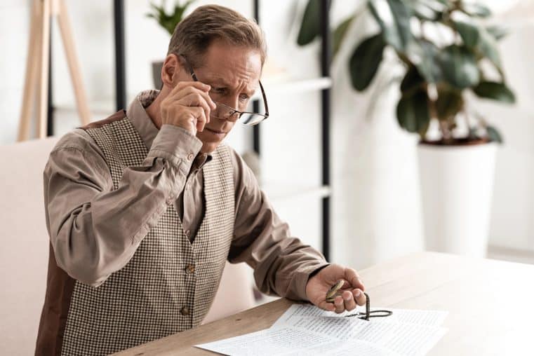 man sitting at a desk looking at his pocket watch