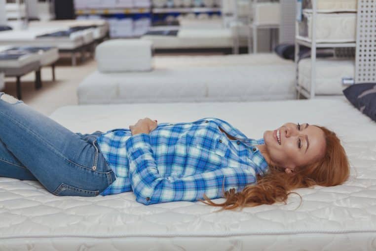 young woman laying on a mattress in the showroom store
