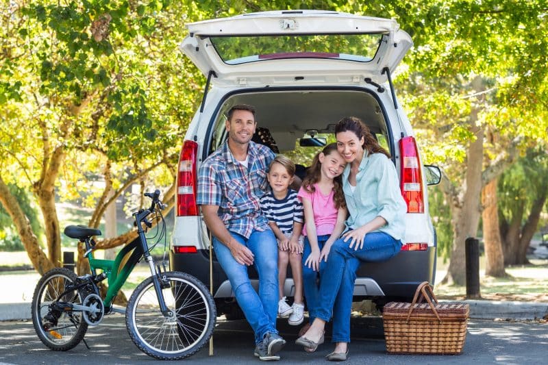 Family getting ready for road trip and sitting in the back of an SUV