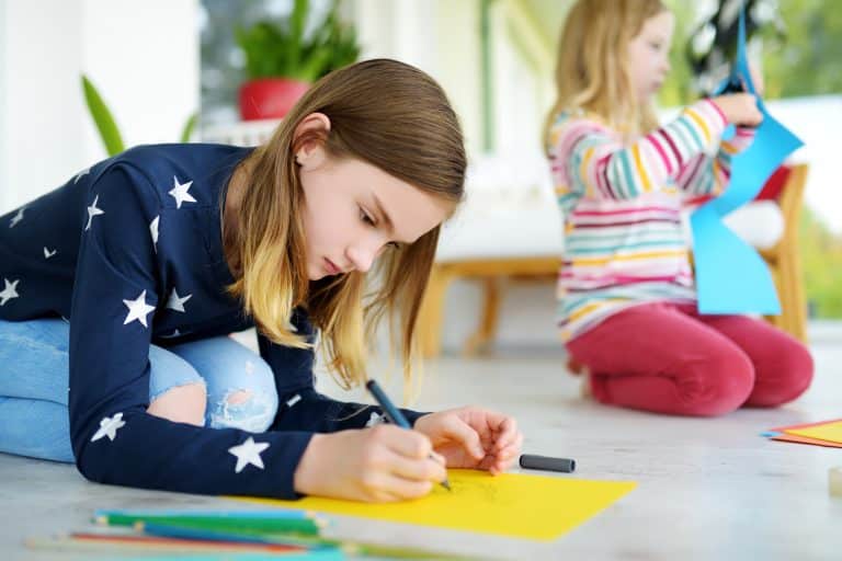 Two young sisters drawing with colorful pencils at home. Creative kids doing crafts together. Education and distance learning for kids. Homeschooling during quarantine. Stay at home entertainment.