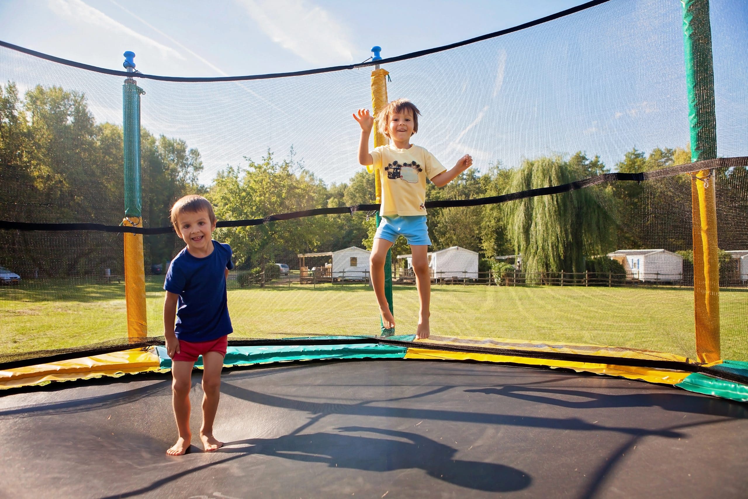 two boys jumping on a backyard trampoline