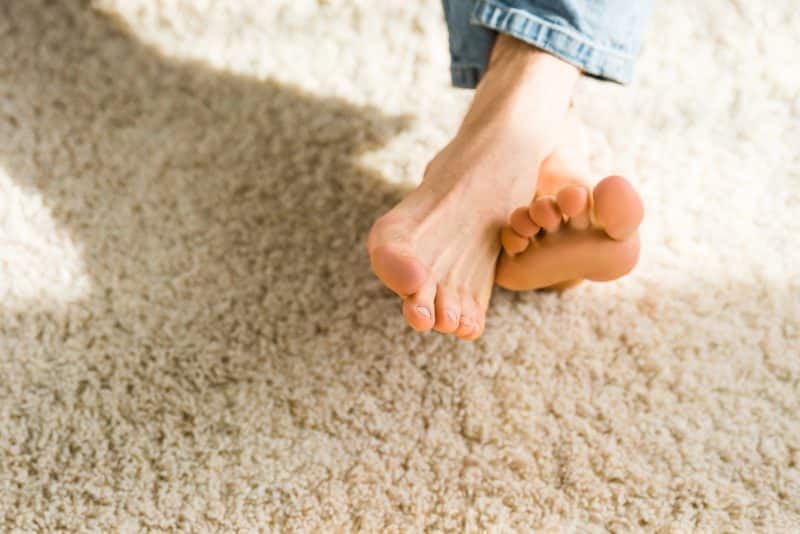 Cropped view of male feet on beige rug