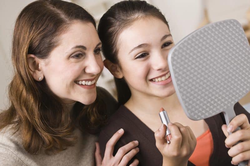 Smiling Mother and Daughter with Lipstick, Looking at Mirror